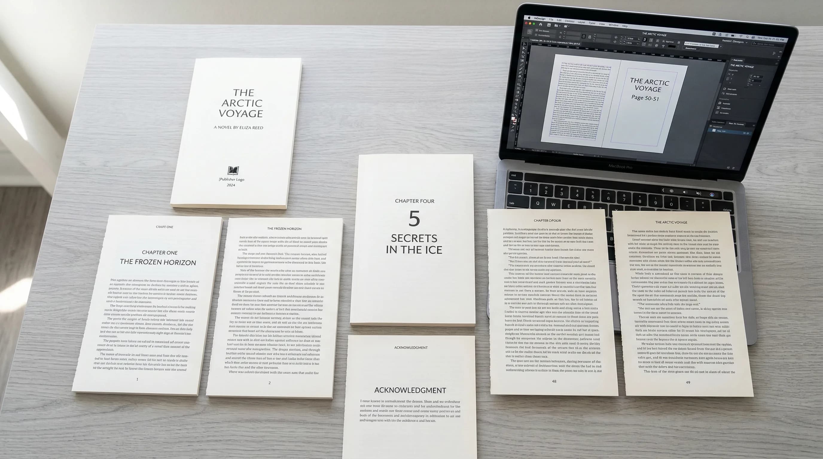 Printed book proof pages spread on a desk next to a laptop showing layout software