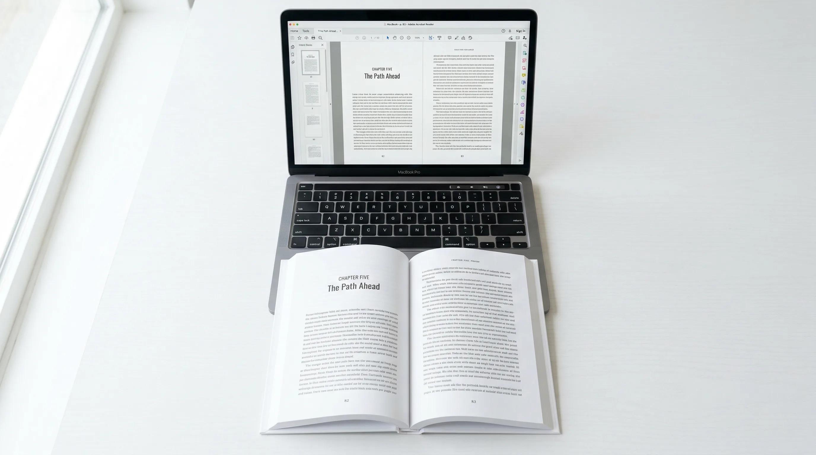 Printed paperback proof copy open on a desk next to a laptop showing the PDF layout